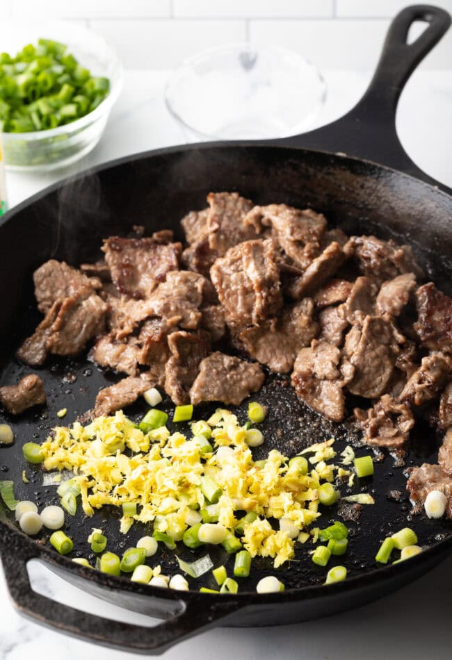 Cooked steak, garlic, and onions in a skillet.