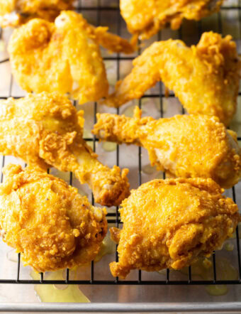 Fried pieces of chicken draining on a wire rack.