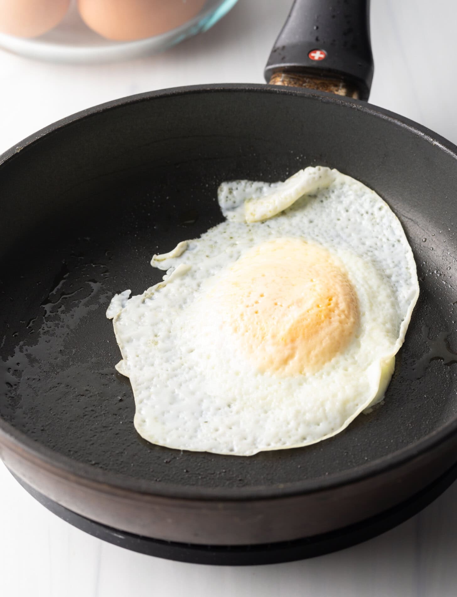 Soft fried egg over easy in a black nonstick skillet.