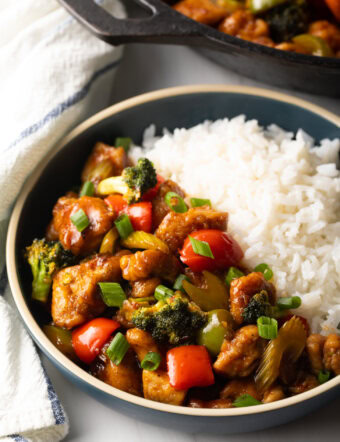 Bowl filled half and half with chicken stir fry and white rice.