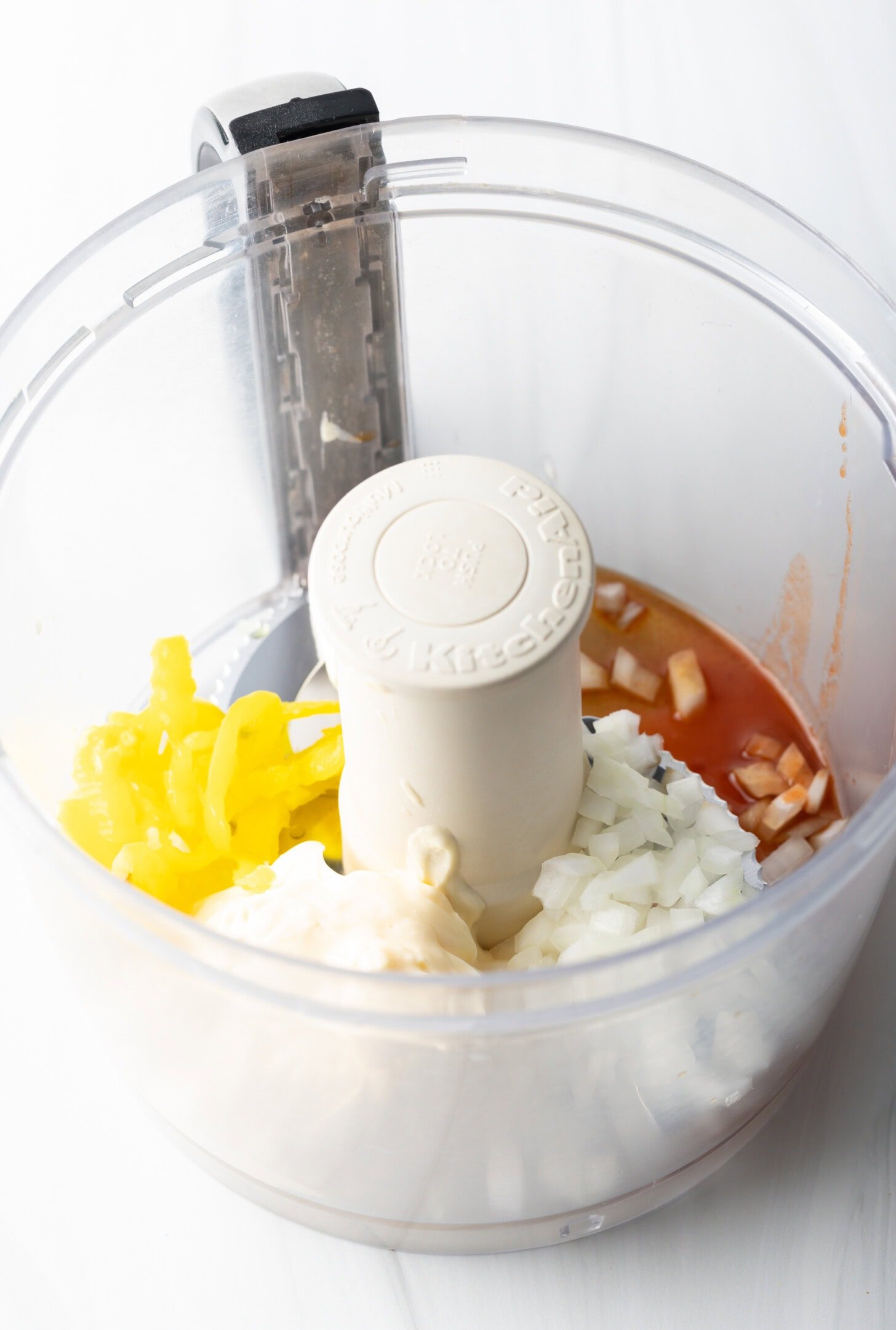 Chopped onions, banana peppers, and hot sauce in a food processor.