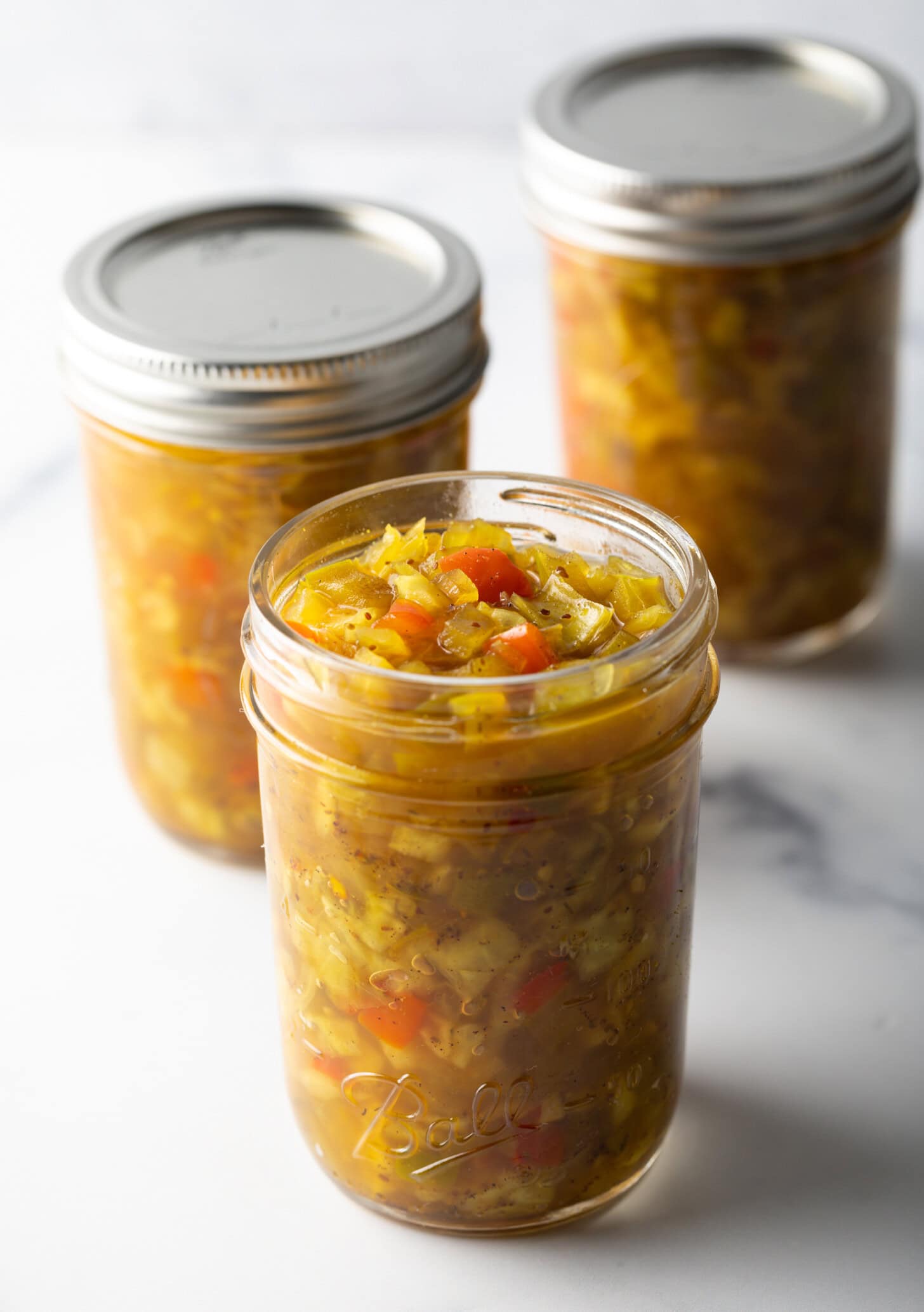 3 glass jars of southern chow chow relish. Front jar has lid off, back two jars have metal lids on.