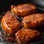 4 pork chops in a black cast iron skillet, covered in a sticky honey soy sauce.