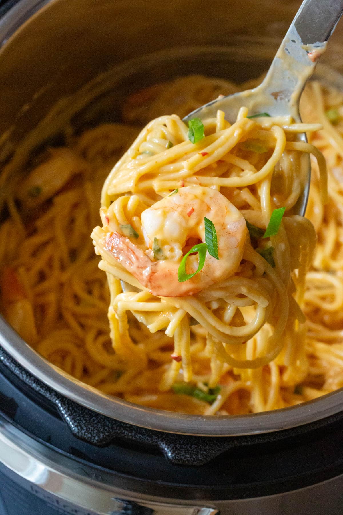 Spoon lifting up a heaping serving of creamy bang bang shrimp pasta. 