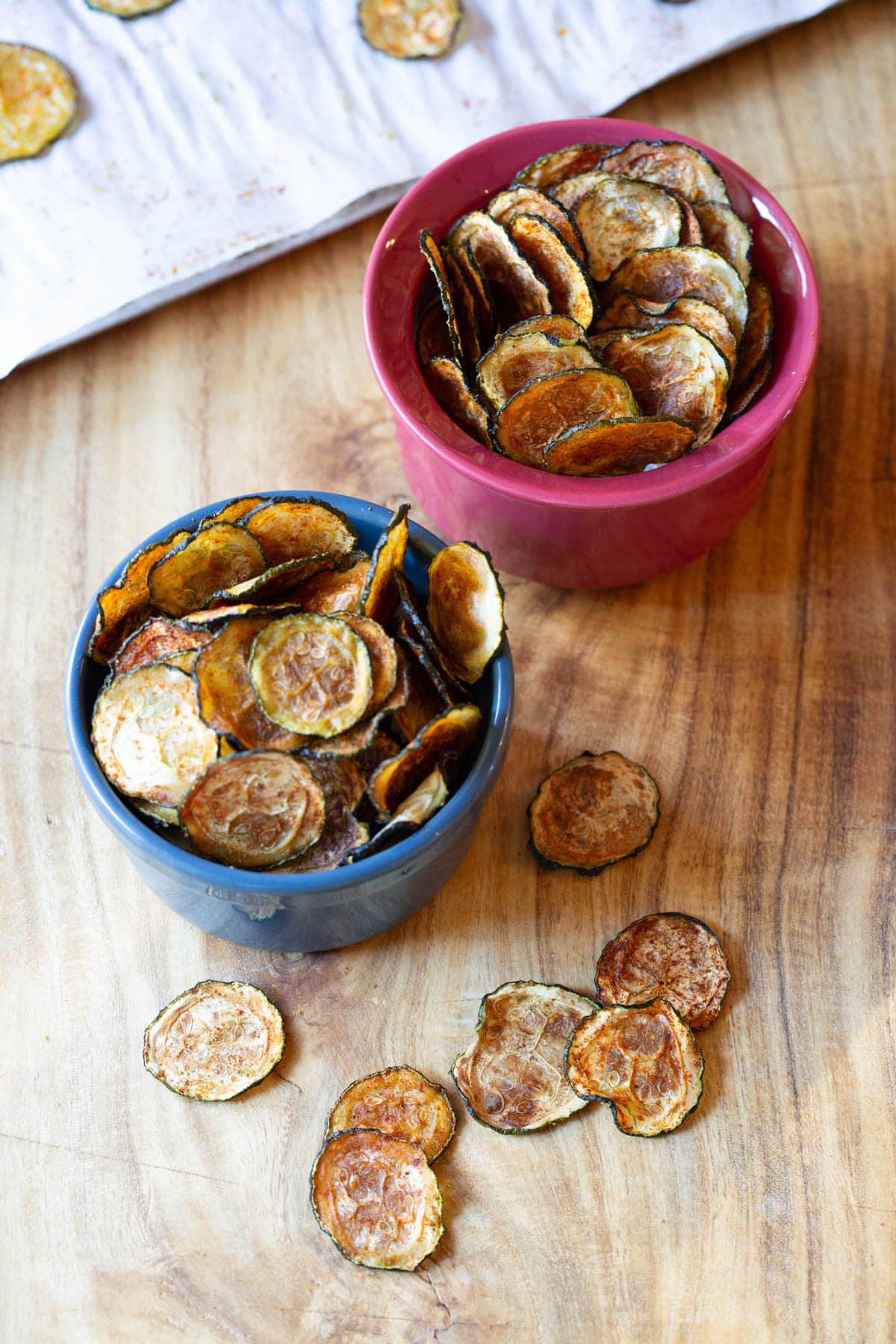 Baked Zucchini Chips #ASpicyPerspective #Healthy #Paleo #Vegan #GlutenFree #Vegetarian #ZucchiniChips #OvenRoasted Chips made from zucchini served in small bowls.