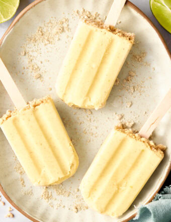 5-Ingredient Key Lime Pudding Pops - lime popsicles on a plate with graham cracker crust garnish