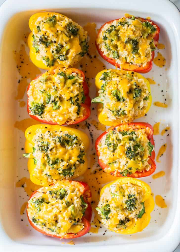Vegetarian Stuffed Peppers after being baked in a baking dish. The cheese is melted and the edges of the broccoli florets are slightly charred.