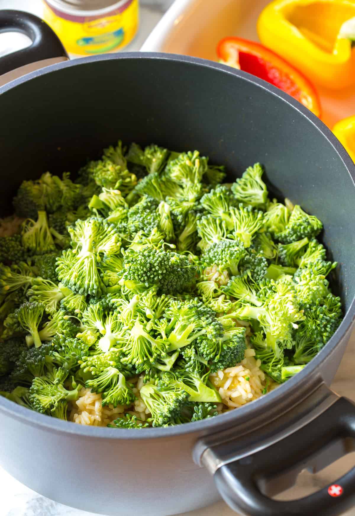 Uncooked broccoli in a cooking pot. You can just see cooked rice underneath.