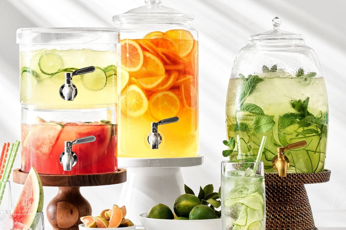 Three drink dispensers with fruity drinks in them. 