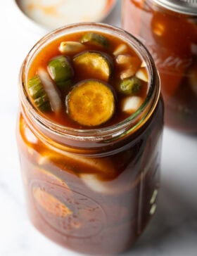 Two glass jars filled with cucumber slices and chamoy seasonings.