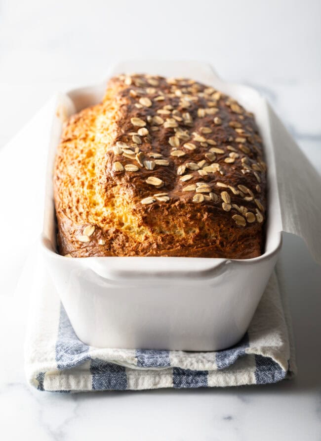 Full loaf of cottage cheese bread with oats in a white loaf pan.