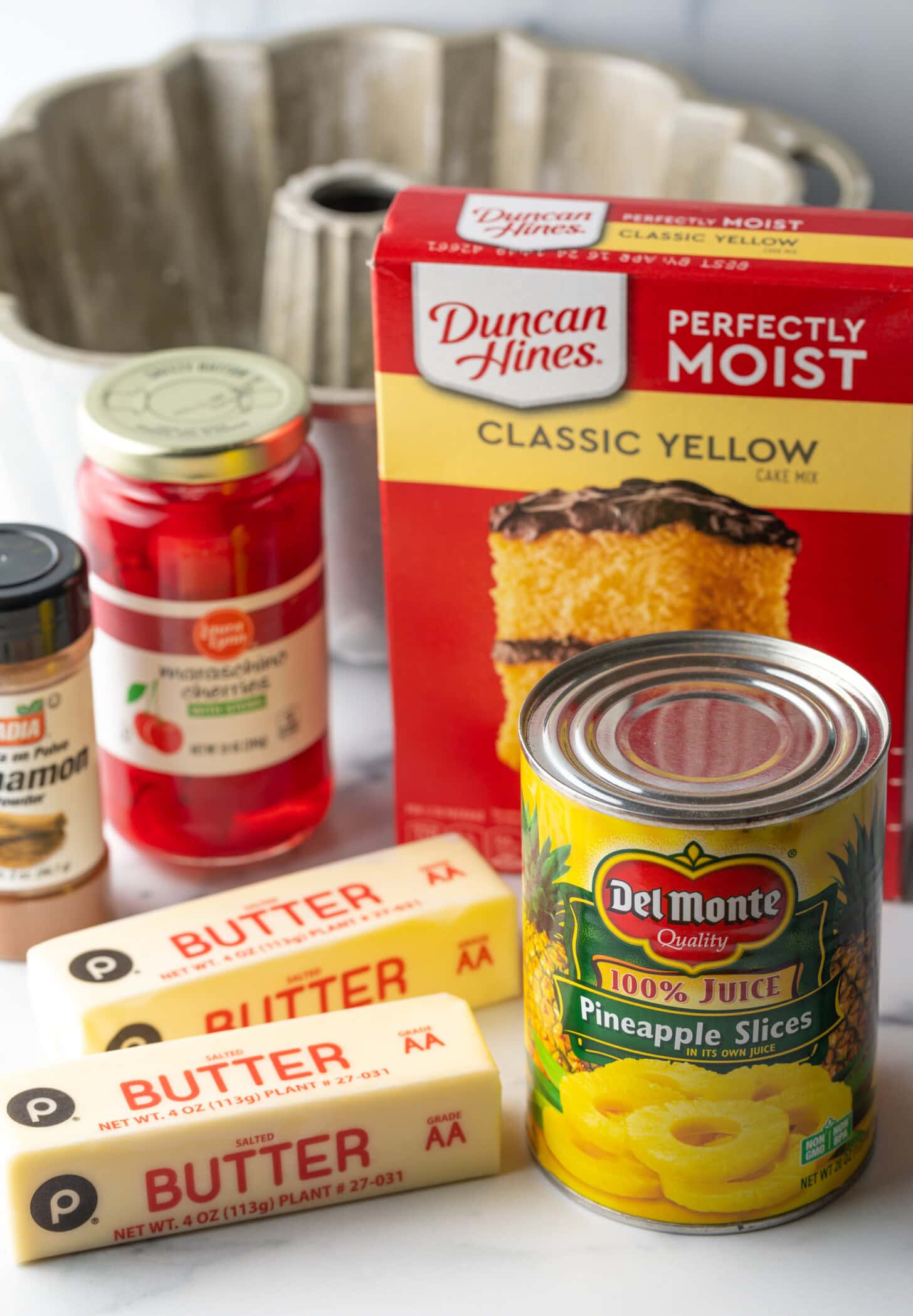 Recipe ingredients: Box of yellow cake mix, jar of maraschino cherries, can of pineapple, two sticks of butter, cinnamon spice.