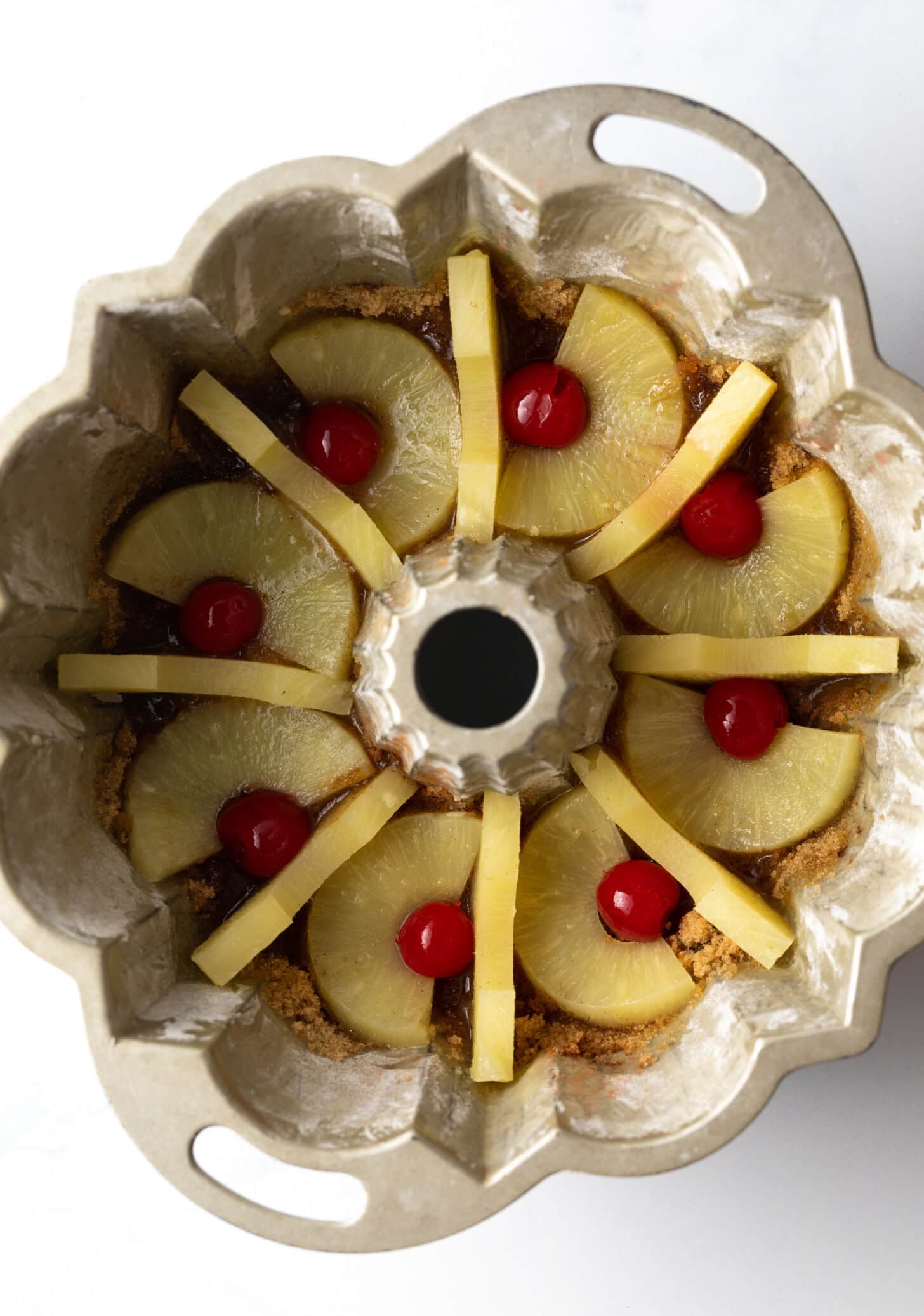 Pineapple and maraschino cherries placed in a bundt pan.