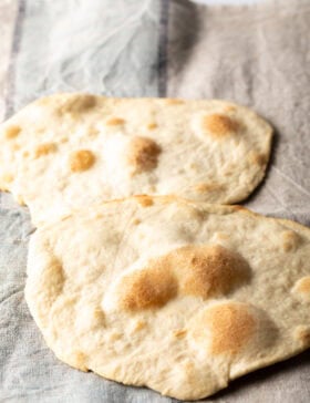 Two pieces of unleavened bread laying on a gray background.