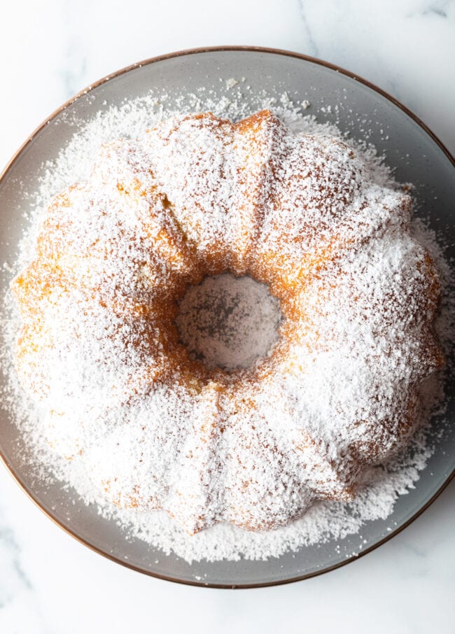 Orange or lemon olive oil bundt cake dusted with powdered sugar on a white plate.