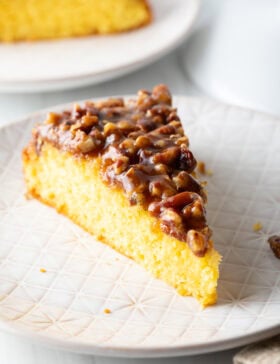 Single slice of upside down pecan cake on a white plate.