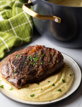 Grilled steak on top of a bed of whipped potatoes.