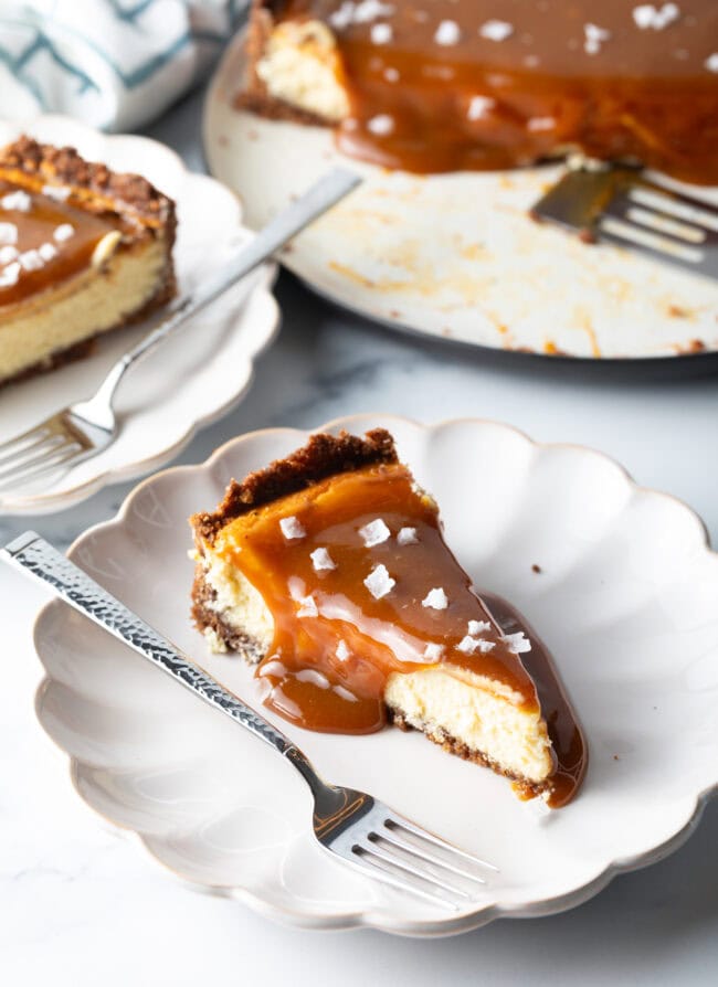 Slice of salted caramel cheesecake on a white plate with a fork.