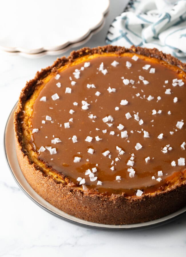 Whole caramel cheesecake with flecked sea salt on top.