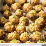Two dozen seafood stuffed mushrooms in a white baking dish.