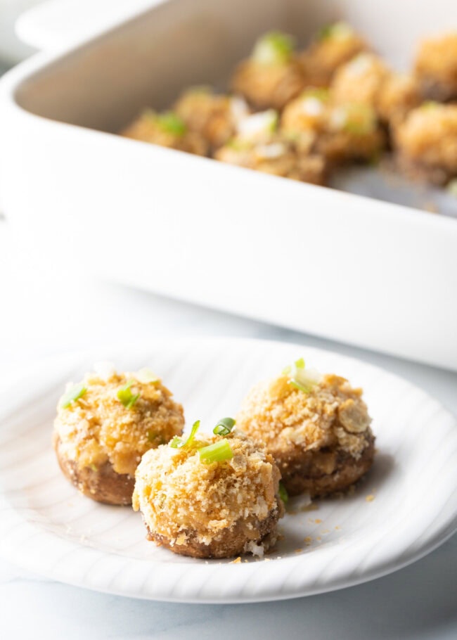 3 baked seafood crab stuffed mushrooms on a white plate.