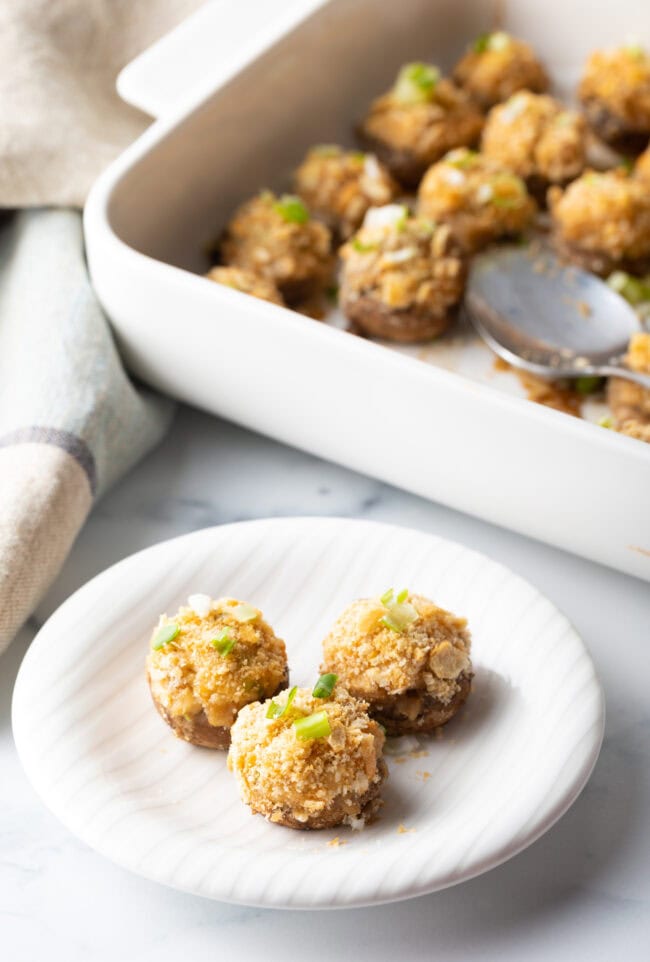 3 baked seafood crab stuffed mushrooms on a white plate.