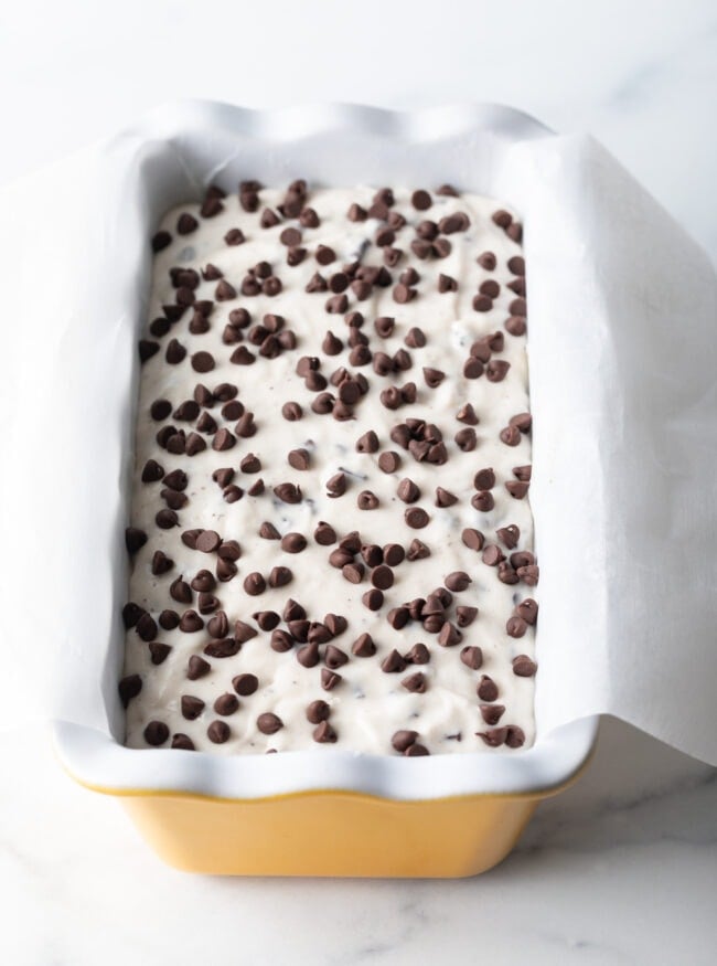 Batter in a yellow ceramic baking pan loaf.