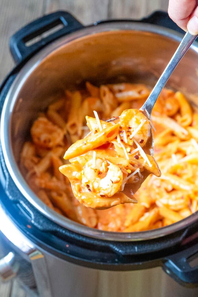 Shrimp pasta in an instant pot with a spoon hovering over it with a bite of pasta. 
