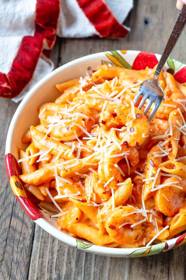 Bowl of penne alla vodka with shrimp with a fork taking a piece of shrimp. I