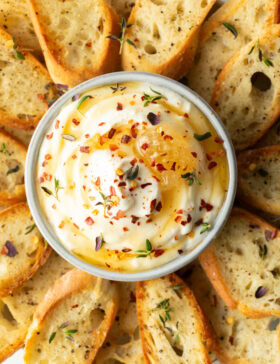 Bowl of whipped ricotta surrounded by slices of baguette, arranged around the ricotta like flower petals.