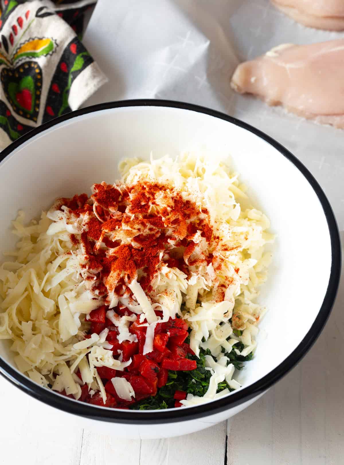 filling for stuffed chicken in bowl - cheese, roasted red peppers, spinach, and spices
