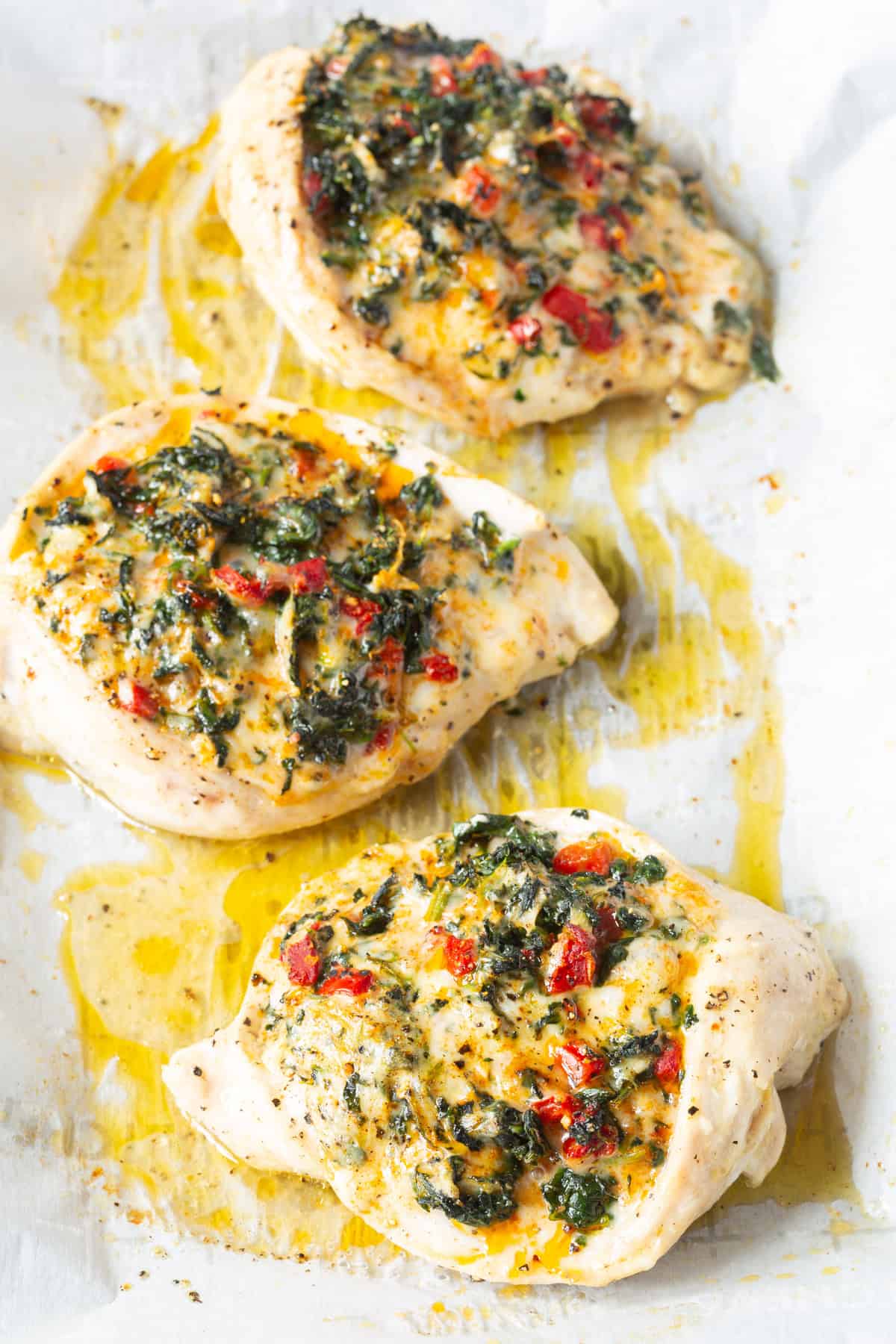 baked chicken pieces with spinach filling in the middle on baking sheets
