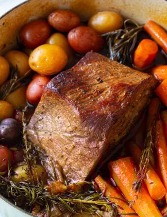 Shredded beef pot roast with carrots and potatoes in a dutch oven.