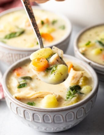 Bowlful of soup with a spoon holding a spoonful to camera.