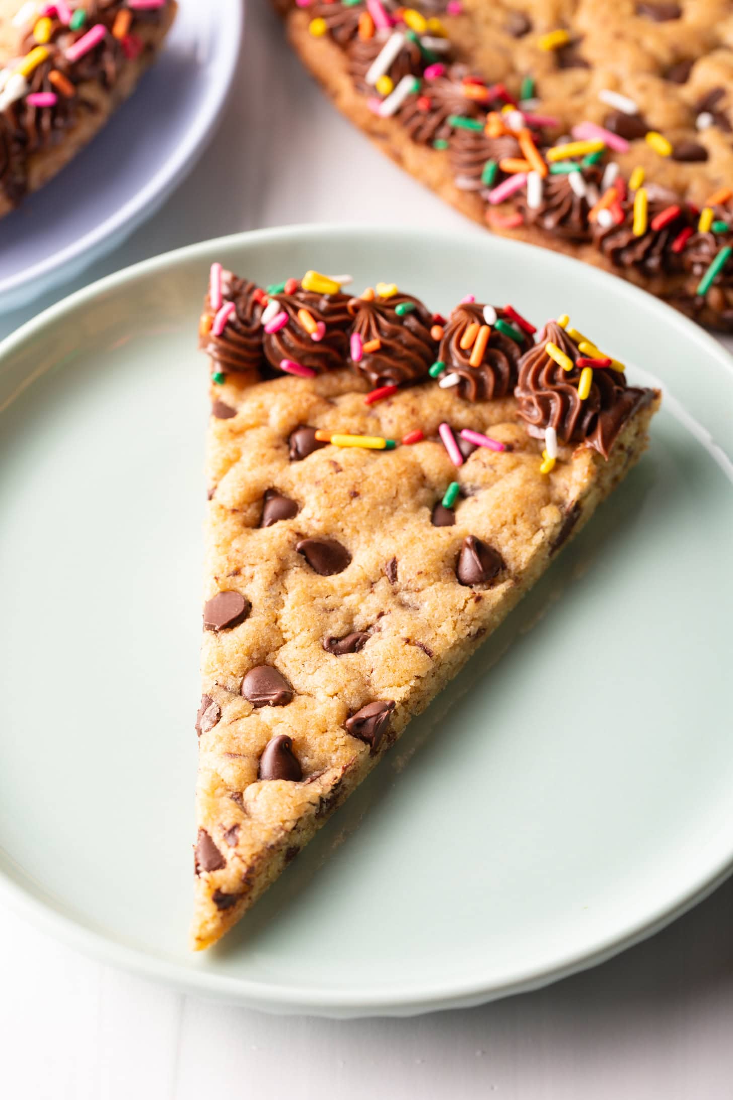 One triangle slice of homemade cookie cake on a pastel blue plate.