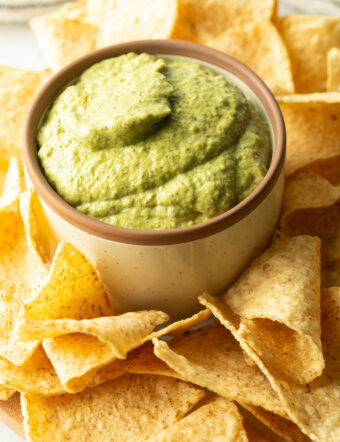 Small bowl of poblano cream sauce surrounded by tortilla chips