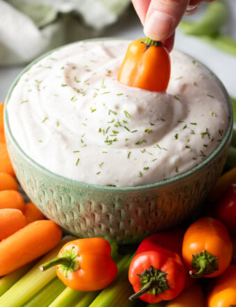 Mini orange pepper dipping into a small green bowl of white cottage cheese dip.