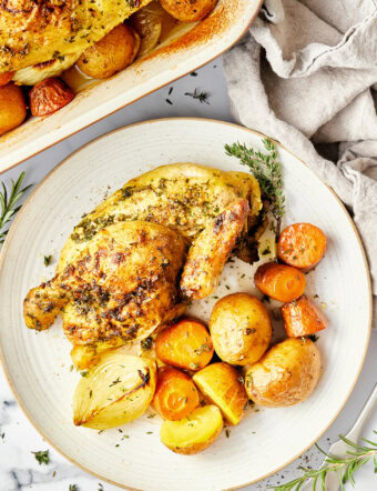 Roasted Game Hens in a roasting pan on a bed of veggies.