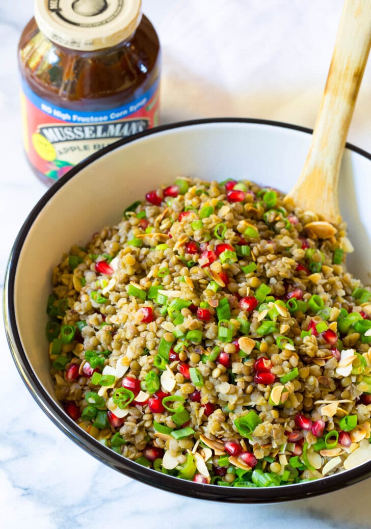 Healthy Lentil Salad with Apple Cider Vinaigrette in a large serving bowl with a wooden spoon. 