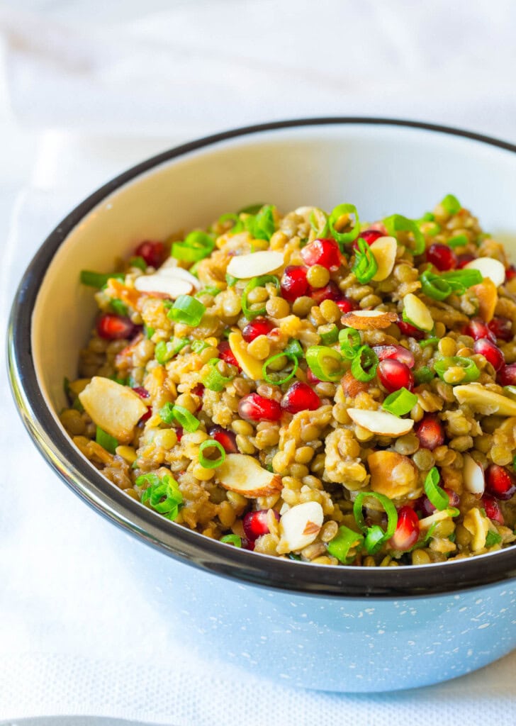 Lentil salad with pomegranate, almonds and scallions in a serving bowl.