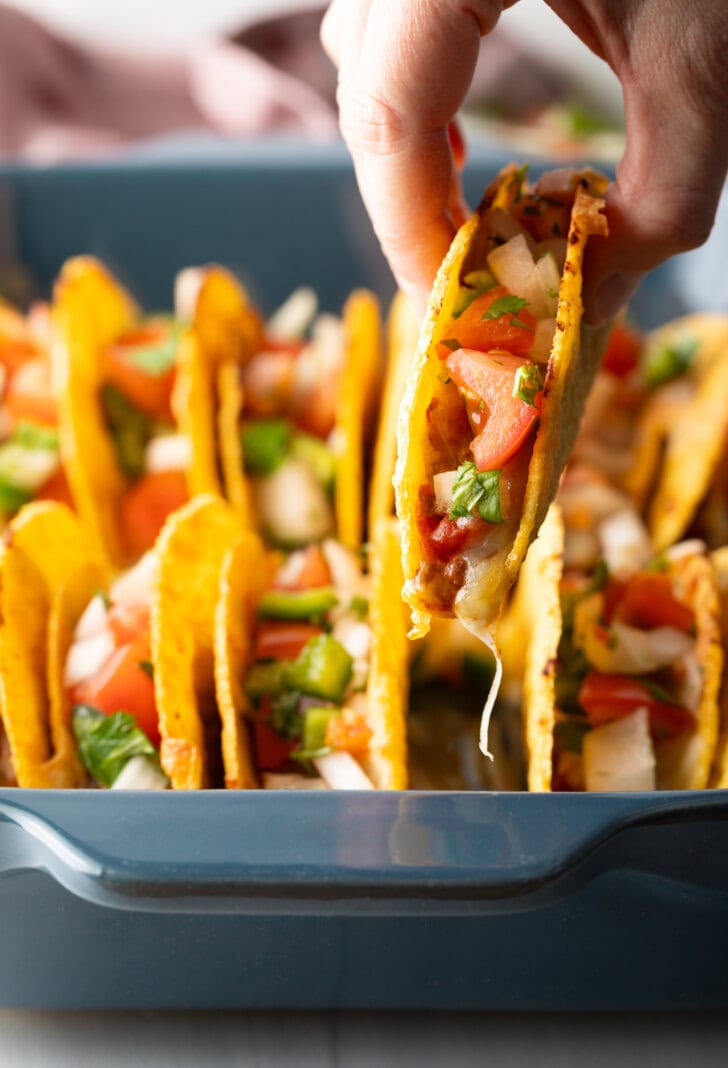 Hand picking up a taco from the tray.