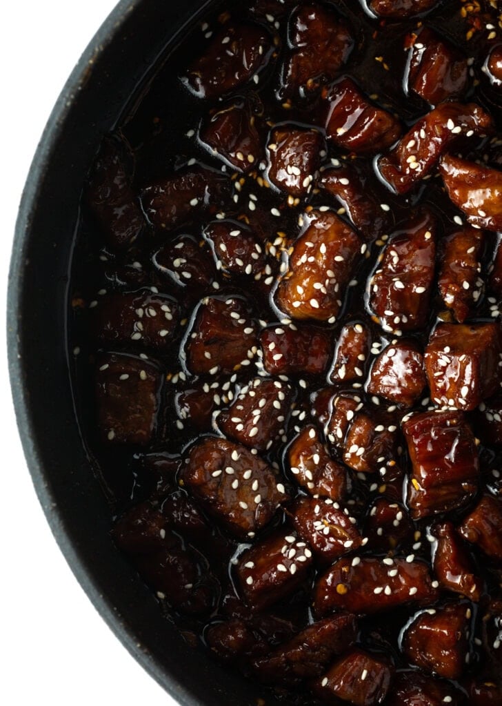 Deep black skillet with chopped beef in a brown sticky teriyaki sauce.