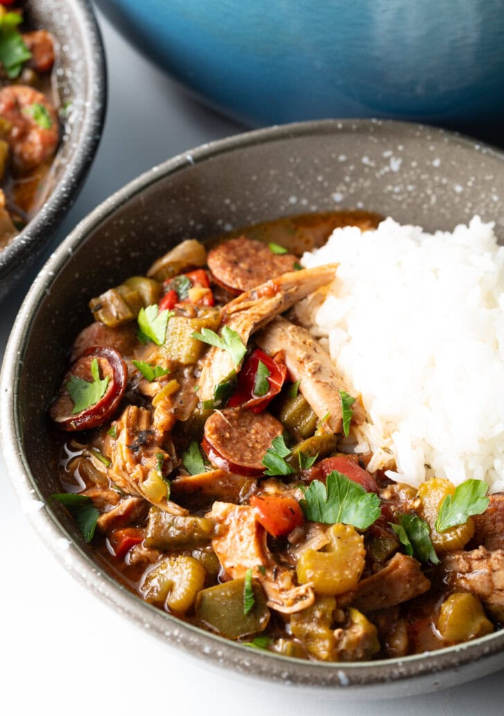 Bowl of chicken sausage gumbo with a scoop of white rice.