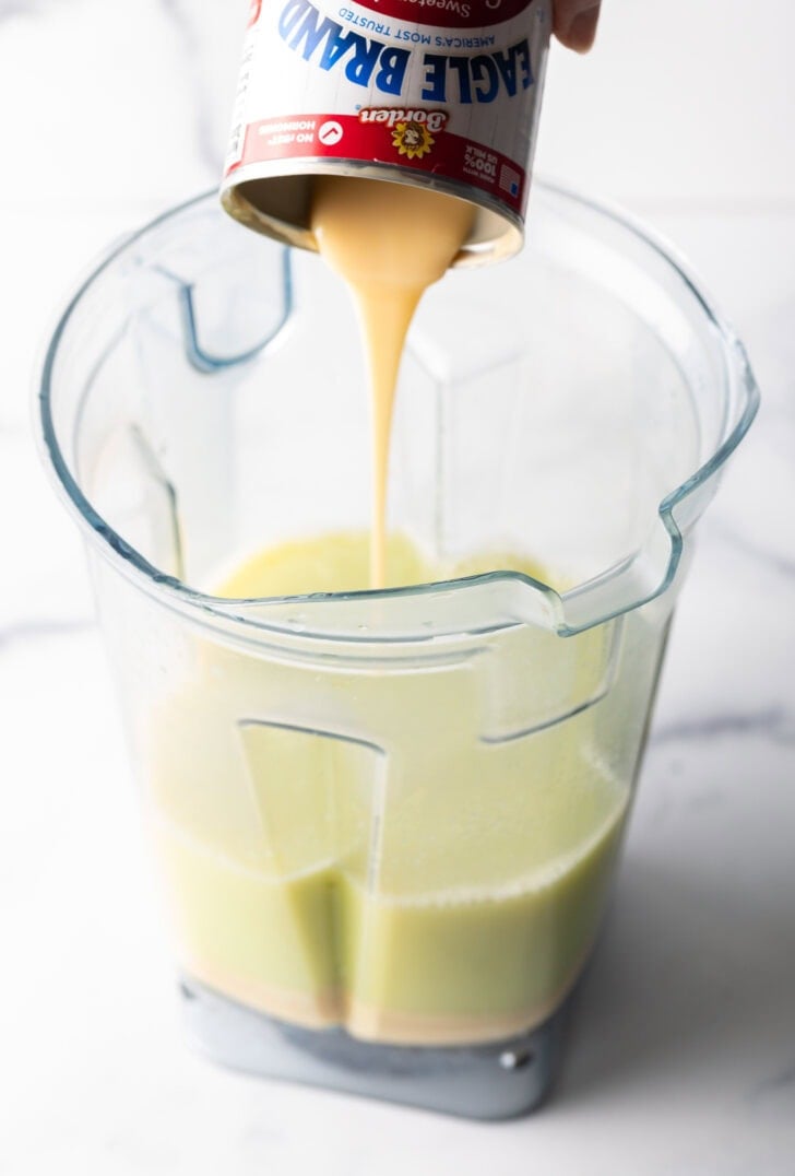 Pouring condensed milk from the can into the blender jar.