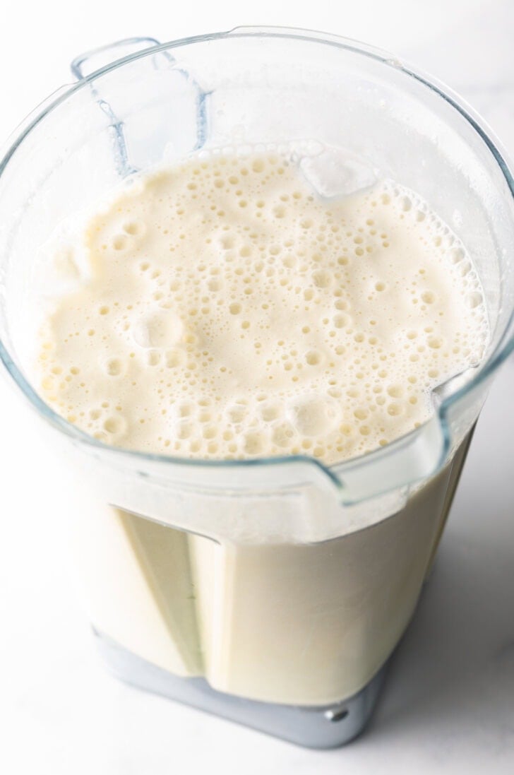 Frothy Brazilian lemonade with limes in a blender jar.