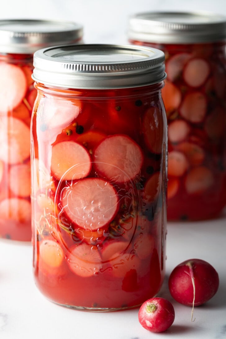 Large sealed glass jars of pickled radish slices.