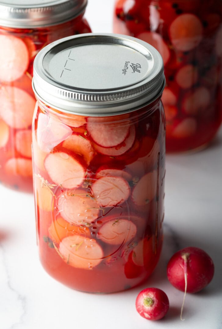 Large sealed glass jars of pickled radish slices.