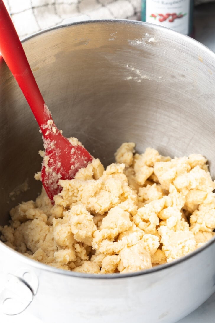 Mixing the cookie dough in a large metal bowl with a red spatula.