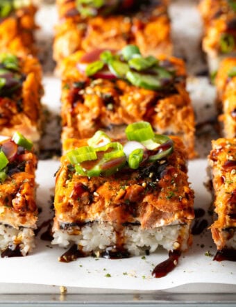 Rows of square slices of sushi bake on a baking sheet.
