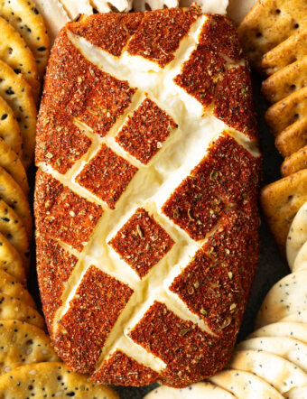 Top down view of a block of spice-coated smoked cream cheese surrounded by various crackers.